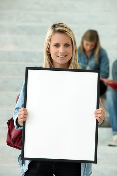 Estudante loira segurando cartaz em branco — Fotografia de Stock