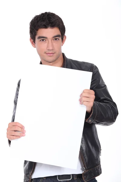 Молодой человек в кожаной куртке держит доску пустой для вашего сообщения — стоковое фото