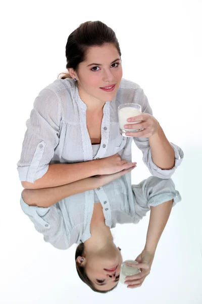 女人在镜像桌上喝一杯牛奶 — 图库照片
