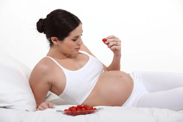 Těhotná žena jíst rajčata — Stock fotografie