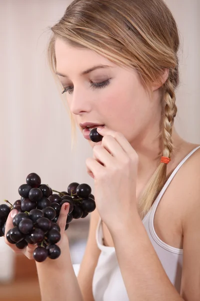Jovem mulher de cabelos justos comendo uvas — Fotografia de Stock