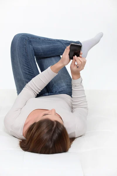 Mulher em seu telefone deitado no chão . — Fotografia de Stock