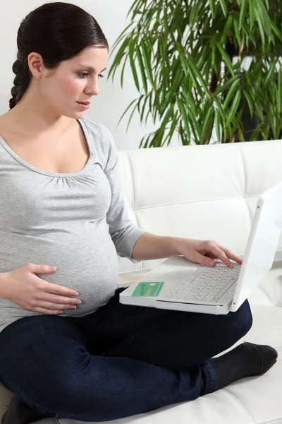 Donna incinta seduta a casa con computer portatile — Foto Stock