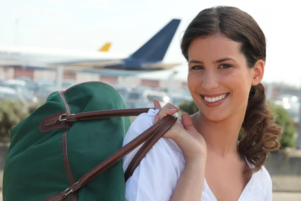 Νεαρή γυναίκα χαμογελώντας με τσάντα ταξιδιού — Φωτογραφία Αρχείου