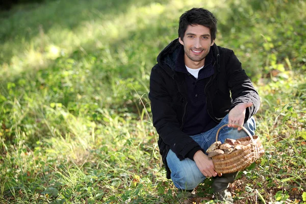 Mann kniete bei Korb mit Pilzen — Stockfoto
