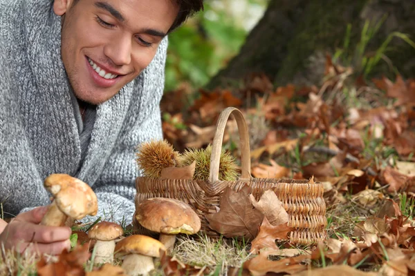 Mann liegt auf dem Boden und sammelt Pilze — Stockfoto