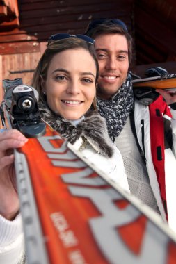 Couple of skiers stood by their chalet clipart