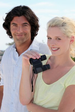 Couple using binoculars on a sunny day clipart