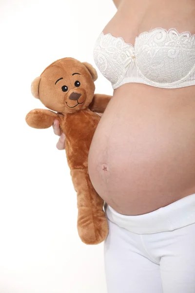Una donna incinta con un orsacchiotto . — Foto Stock