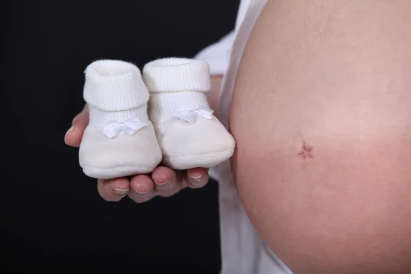 Kobieta w ciąży z kapcie w ręku — Zdjęcie stockowe