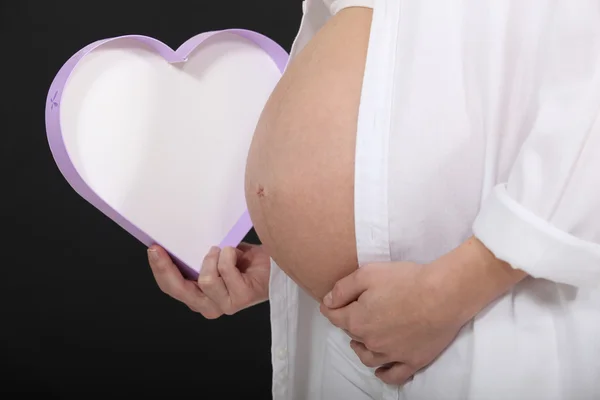 Mulher grávida segurando uma caixa em forma de coração — Fotografia de Stock