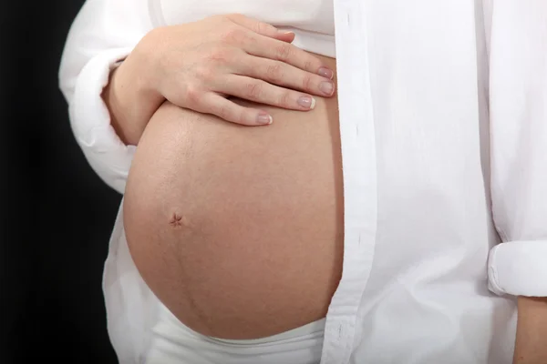 Женщина трогает ее беременный живот — стоковое фото