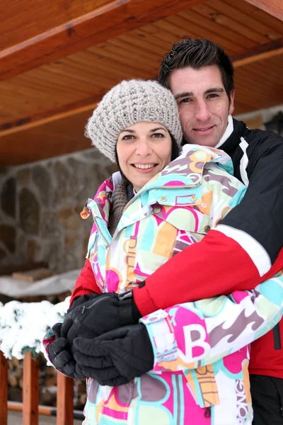 Couple hugging by their winter chalet — Stock Photo, Image