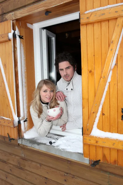 Couple at a window of a cottage — Stock Photo, Image