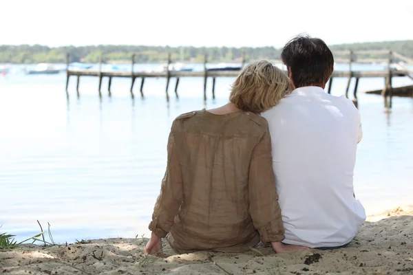 Пара сидящих на берегу озера — стоковое фото
