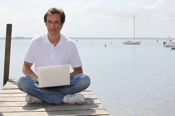 Muž s počítačem v doku — Stock fotografie