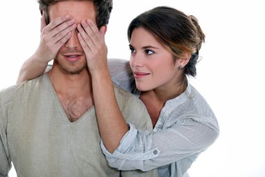 Young woman holding her hands over a man's eyes clipart