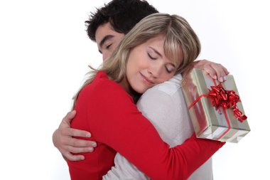 Young man holding girlfriend in arms after giving present clipart