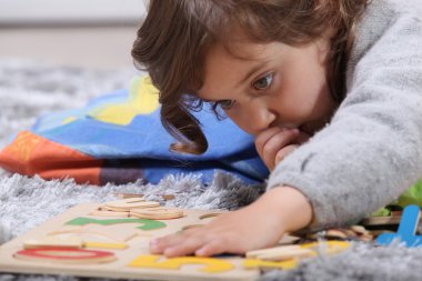 Child playing with a puzzle clipart