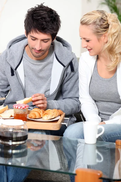 Para jedząc śniadanie na kanapie — Zdjęcie stockowe