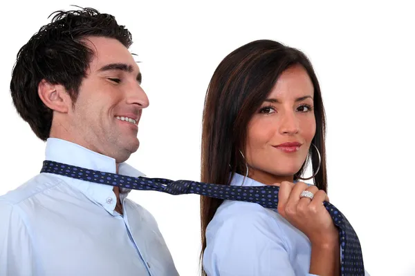 Mujer liderando a un hombre por su corbata — Foto de Stock