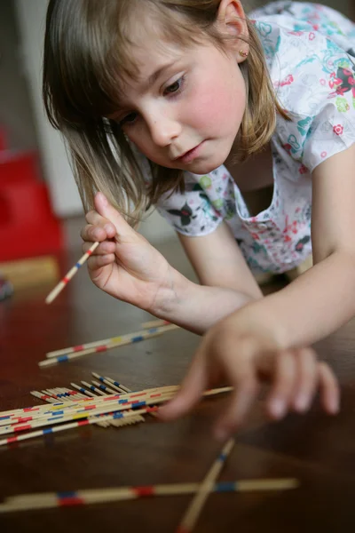 Ένα μικρό κορίτσι παιχνίδι pick-up μπαστούνια — Φωτογραφία Αρχείου