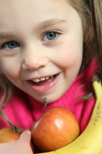 Liten flicka håller i äpplen och bananer — Stock fotografie