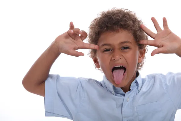 Ung pojke dra ett ansikte och fast hans tunga — Stockfoto
