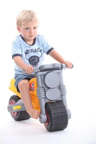 En liten gutt på en lekemotorsykkel – stockfoto