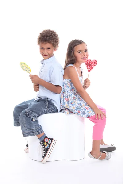 Ein Bruder und seine Schwester genießen einen Lollypop. — Stockfoto