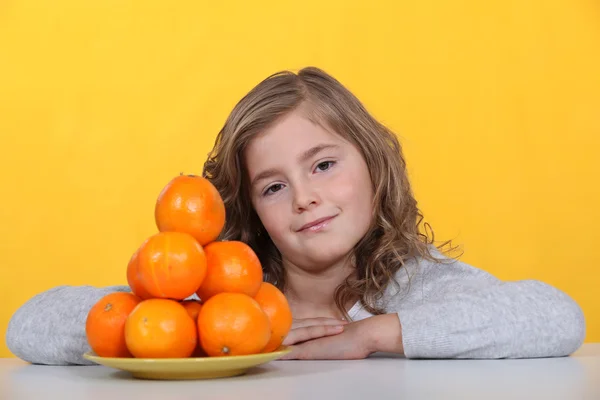Girl with a pyramid of oranges — Stock Photo, Image
