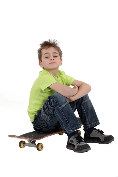 Мальчик сидит на скейтборде — стоковое фото