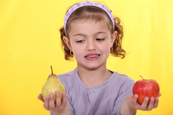 Menina escolhendo entre maçã e pêra — Fotografia de Stock