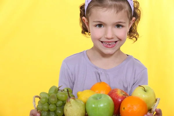 Petite fille debout avec arrangement de fruits — Photo