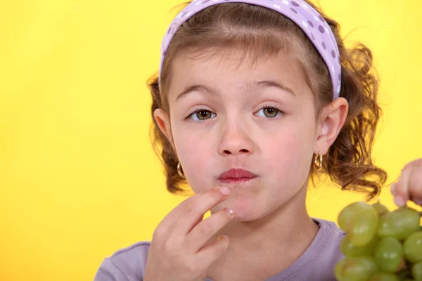 Little girl eating bunch of green grapes — Stock Photo, Image