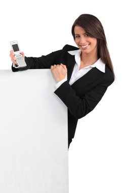 Smiling smart young woman with a fliptop phone and a blank board ready for your text or image clipart