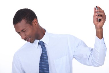 Excited black man wincing and holding a cell phone in his hand clipart