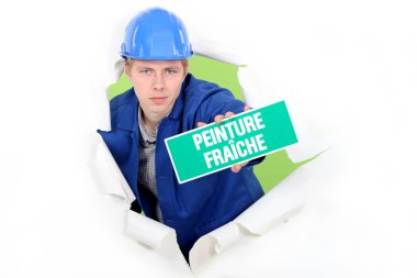 Tradesman holding a 'Wet Paint' sign clipart