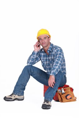 Young tradesman on the phone with customer clipart