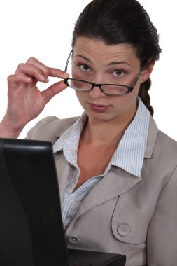 Serious businesswoman watching over her glasses clipart