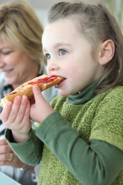 Little girl eating jam on toast for breakfast clipart