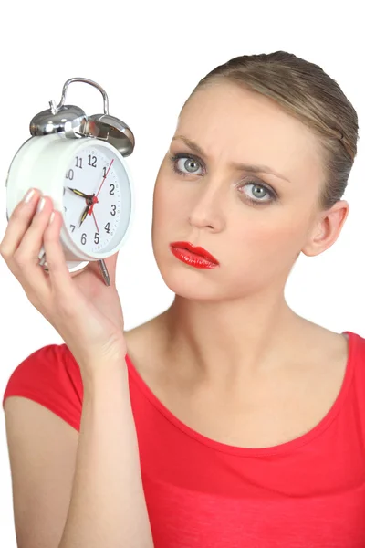 Serious looking blond woman holding alarm clock — Stock Photo, Image