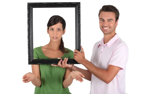 Playful couple stood with empty picture frame — Stock Photo, Image