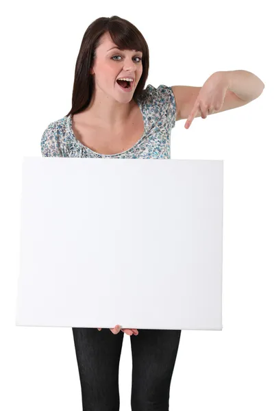 Young woman pointing at a blank board — Stock Photo, Image