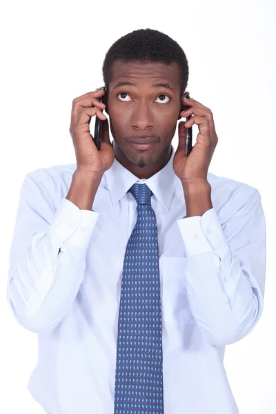 African businessman holding two telephones — Stock Photo, Image