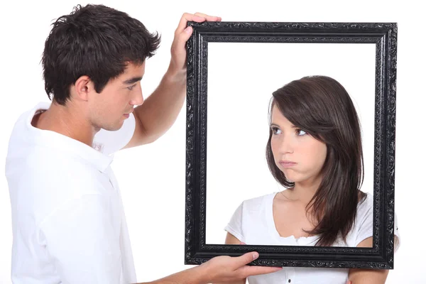 Young couple holding empty picture frame — Stock Photo, Image
