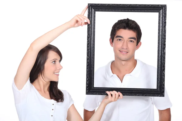 Couple stood with empty picture frame — Stock Photo, Image