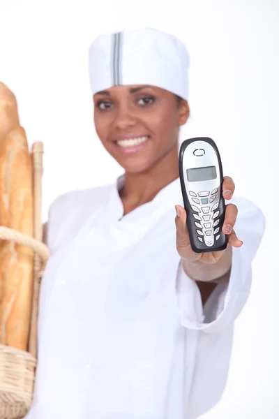 Працівник хлібопекарні тримає телефон — стокове фото