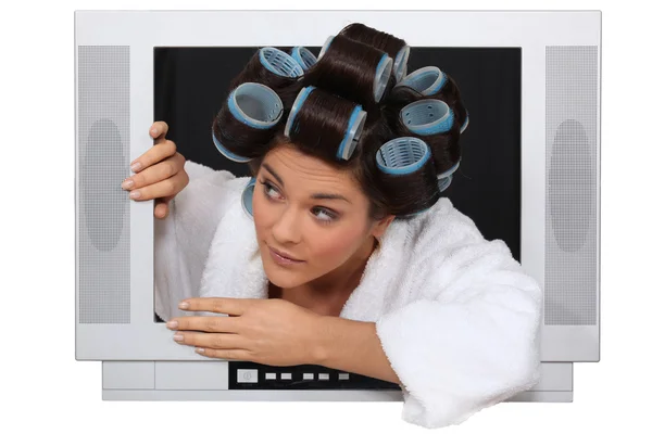 Woman wearing hair rollers escaping from television — Stock Photo, Image