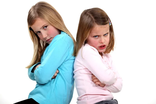 Kleine meisjes met sulky expressie zitten back-to-back — Stockfoto
